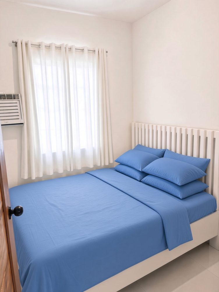 Bedroom 1 with a queen bed, blue bedding and white curtains