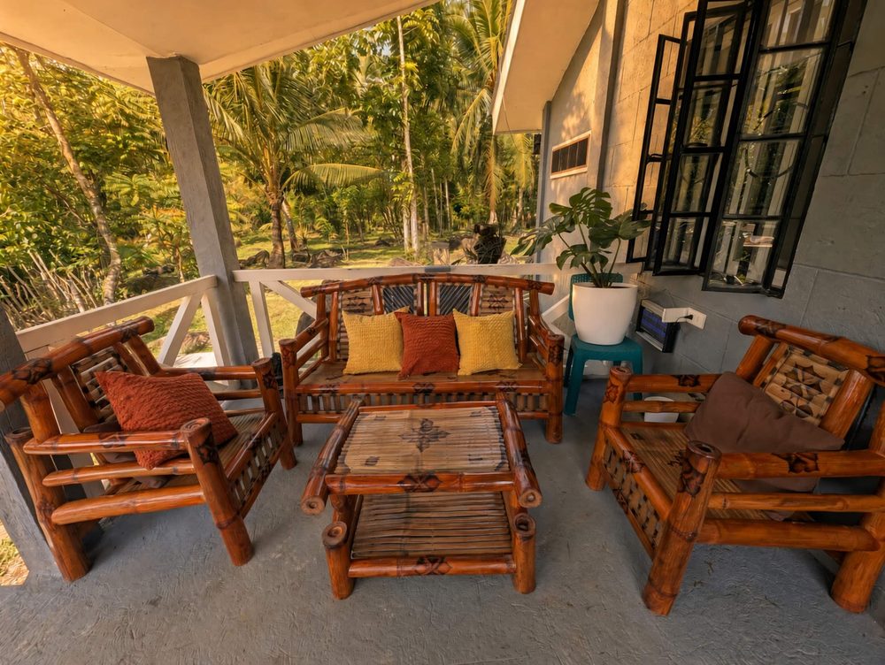 Covered porch with bamboo chairs, a low table and plants